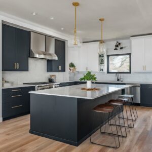 A modern two tone kitchen featuring black and white cabinets, a large island, pendant lighting, and wooden bar stools.